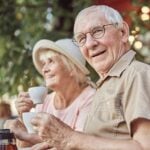 Old man smiling while holding a coffee cup