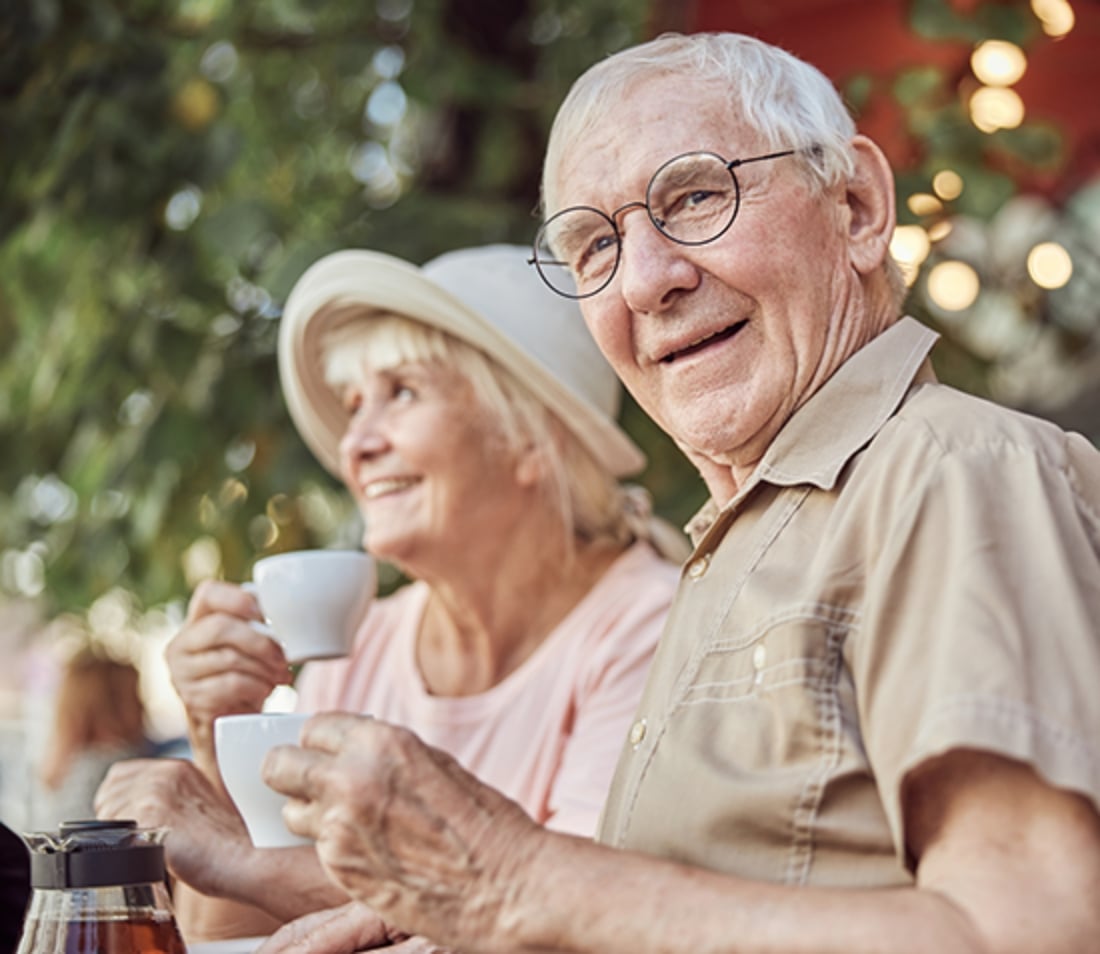 Old man smiling while holding a coffee cup