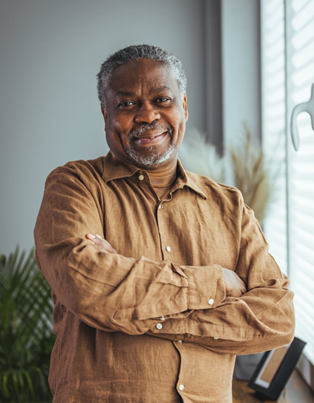 Older black gentleman standing with his arms crossed and smiling