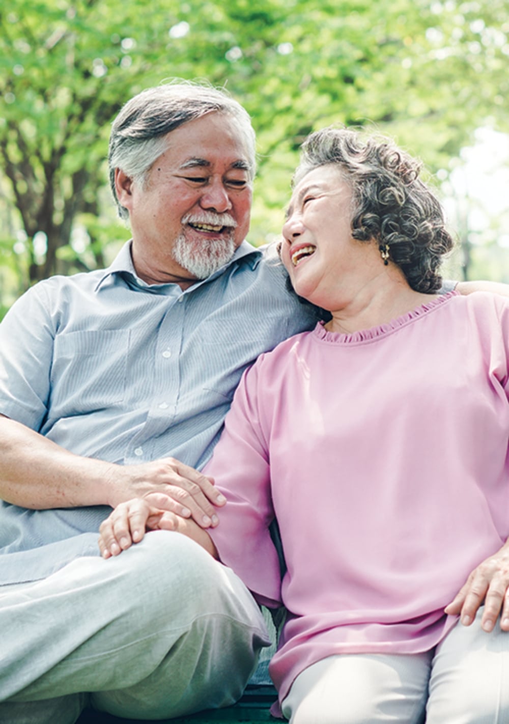 Mature Asian couple laughing outside while sitting