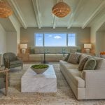 This is a photo of The Seville's assisted living community room, featuring doors that lead to the outdoor community room terrace, comfortable seating, and a large TV.