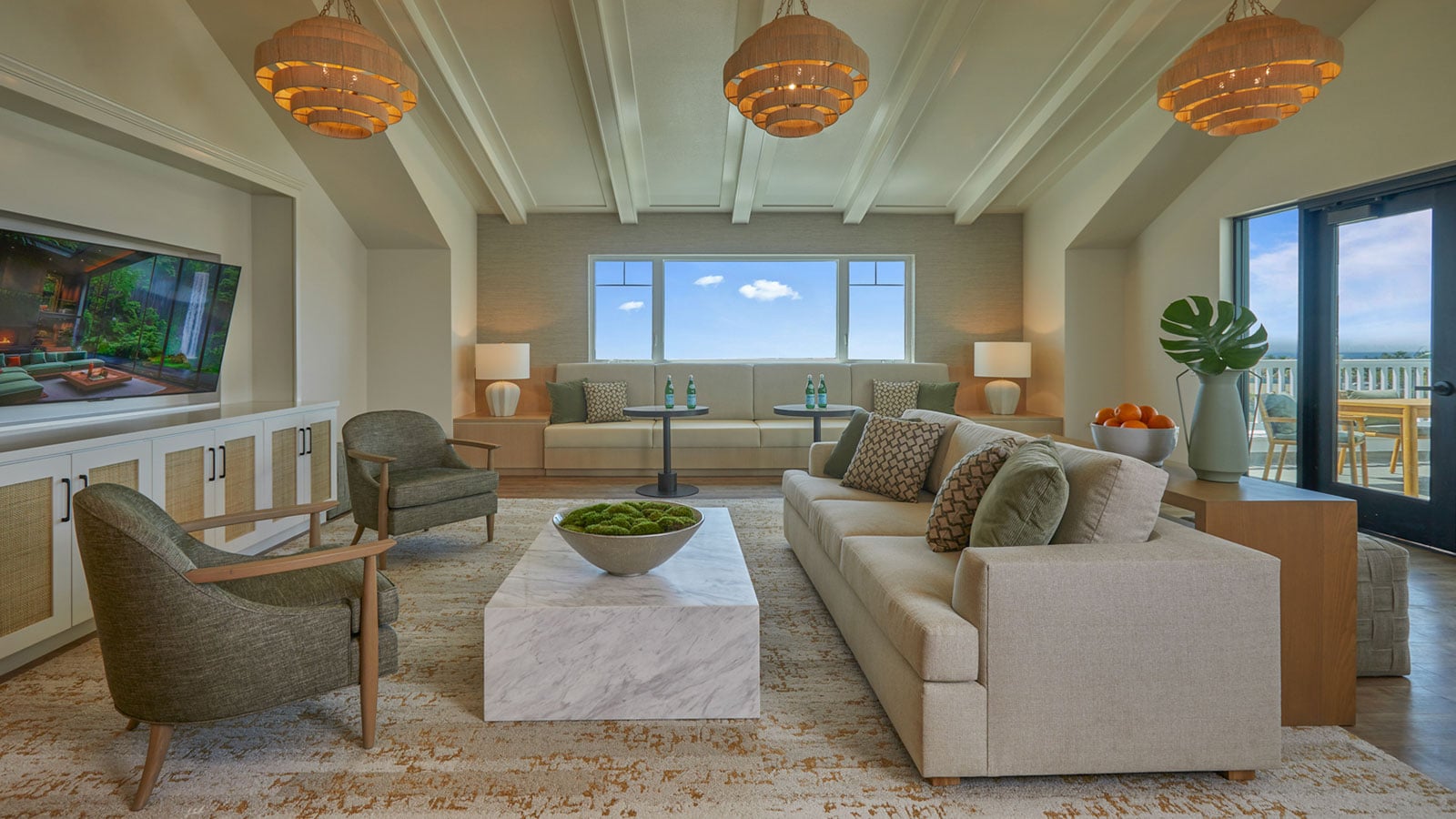 This is a photo of The Seville's assisted living community room, featuring doors that lead to the outdoor community room terrace, comfortable seating, and a large TV.