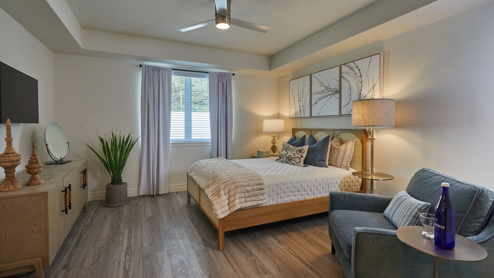 This is a photo of The Seville's model apartment bedroom. The bedroom features a bright window and a queen-sized bed.