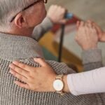 hand resting on the back of a senior man learning about the differences in care